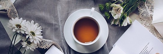 Tisch mit Kaffeetasse und weißen Blumen.