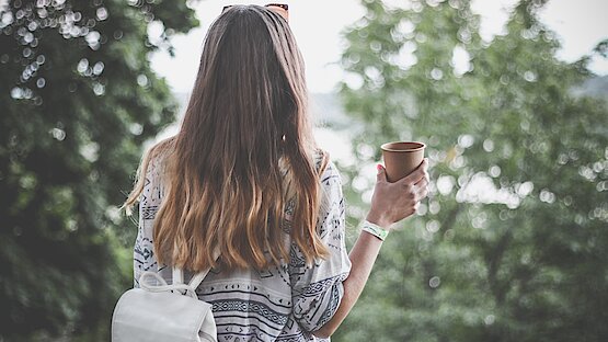 Frau in Natur mit Kaffeetasse in der Hand
